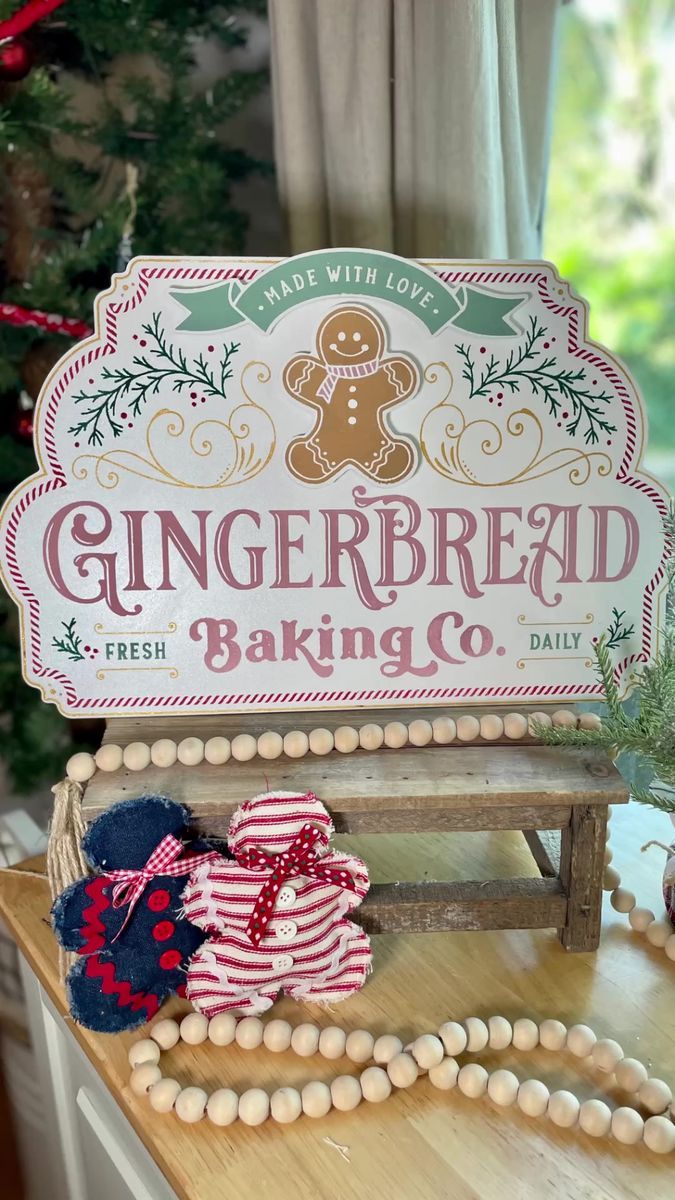 a gingerbread baking co sign sitting on top of a wooden table next to a christmas tree