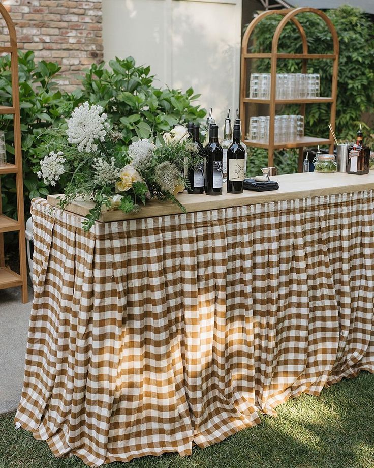 the table is covered with gingham cloths and bottles of wine on it