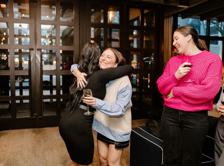 two women hugging each other in front of a group of people