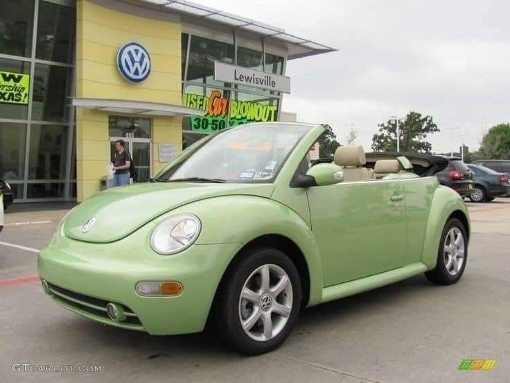 a green car parked in front of a volkswagen dealership