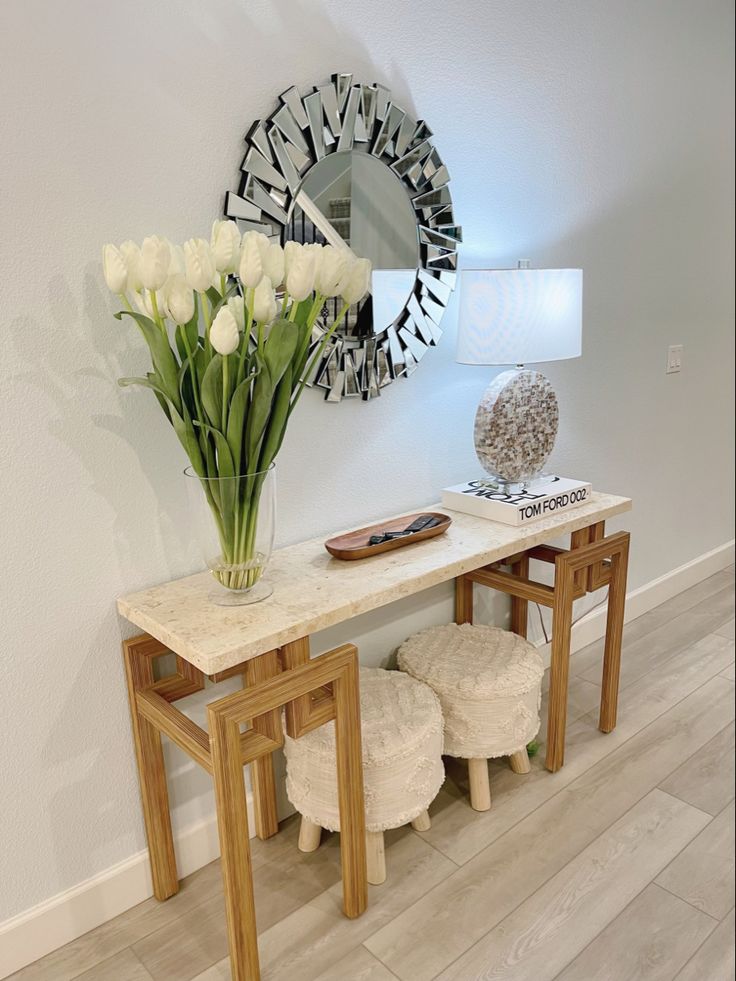 a vase with white flowers sitting on top of a table next to two stools