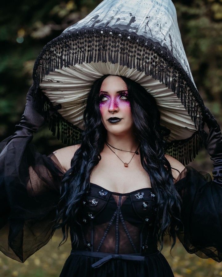 a woman wearing a hat with feathers on it's head and makeup painted pink