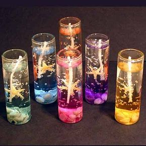 five different colored candles sitting next to each other on a black surface with water and bubbles in them