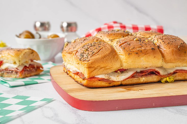 a sub sandwich sitting on top of a wooden cutting board