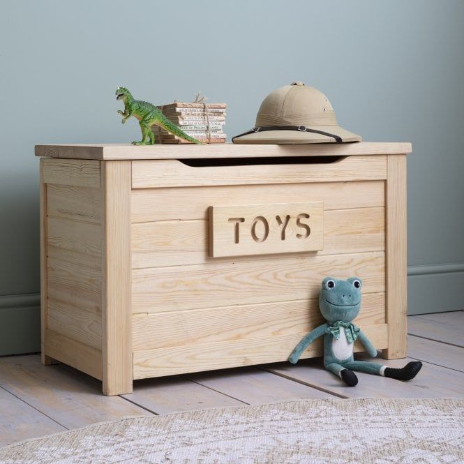 a toy chest with toys in it on the floor next to a stuffed animal and hat