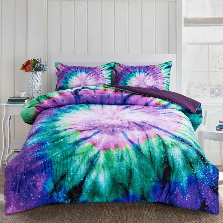 a bed with purple, green and blue tie dye comforter set on top of it