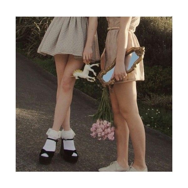 two young women standing next to each other with flowers in their hands and one holding a mirror