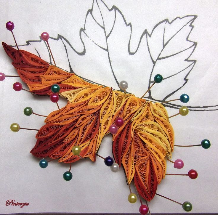 an orange and yellow leaf with beads on the bottom is made out of paper, which has been cut into smaller leaves