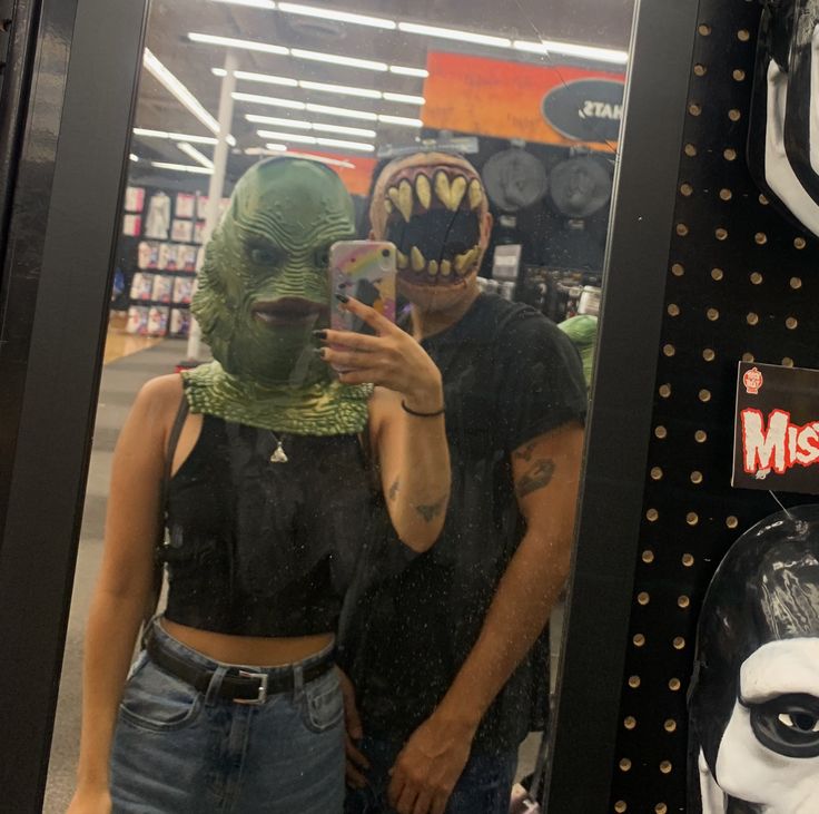 a person taking a selfie in front of a mirror with an alien mask on