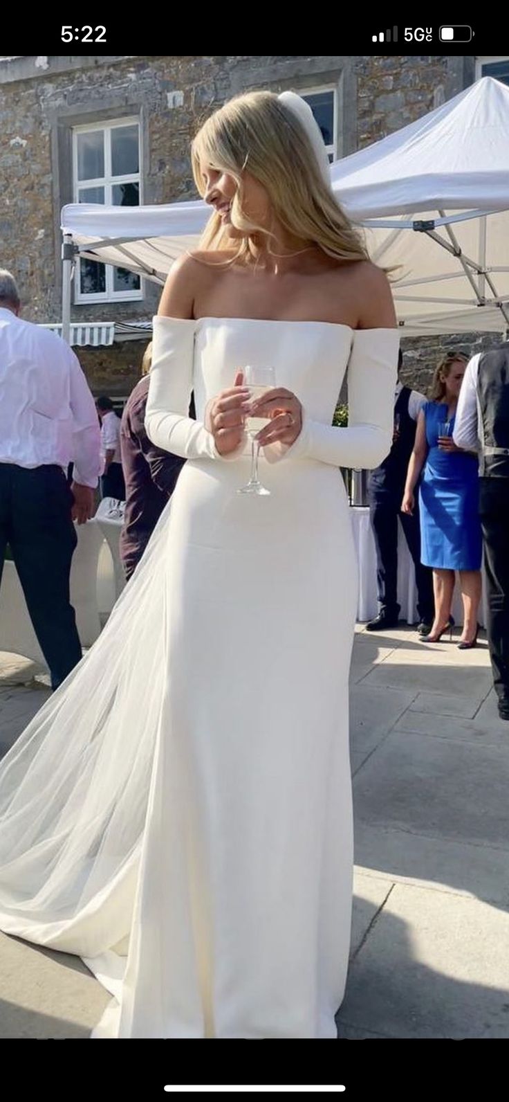 a woman in a white wedding dress walking down the street with her hand on her hip