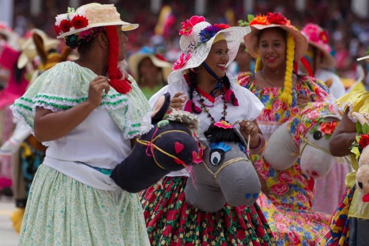 several women in colorful dresses and hats walking with stuffed animals