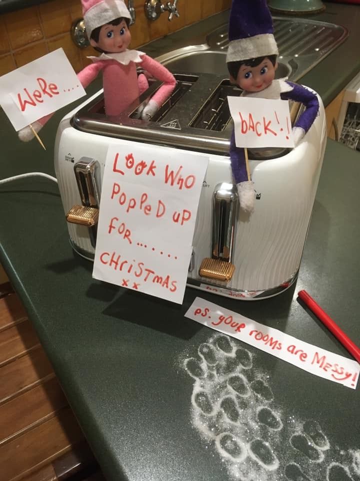 two elfs sitting on top of a toaster with signs in front of them