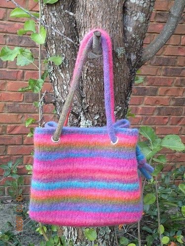 a multicolored bag hanging from a tree in front of a brick wall,