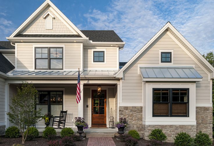 a white house with black shutters and an american flag on the front door is shown