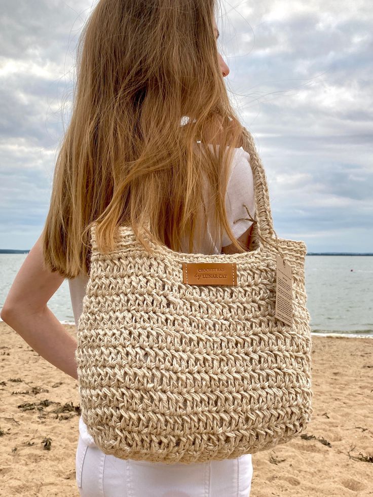 a woman carrying a crocheted bag on the beach