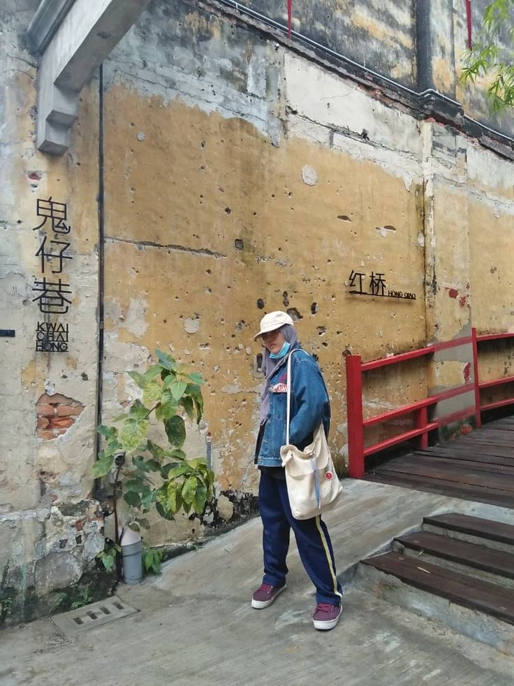 an old man is walking down the street in front of a building with graffiti on it