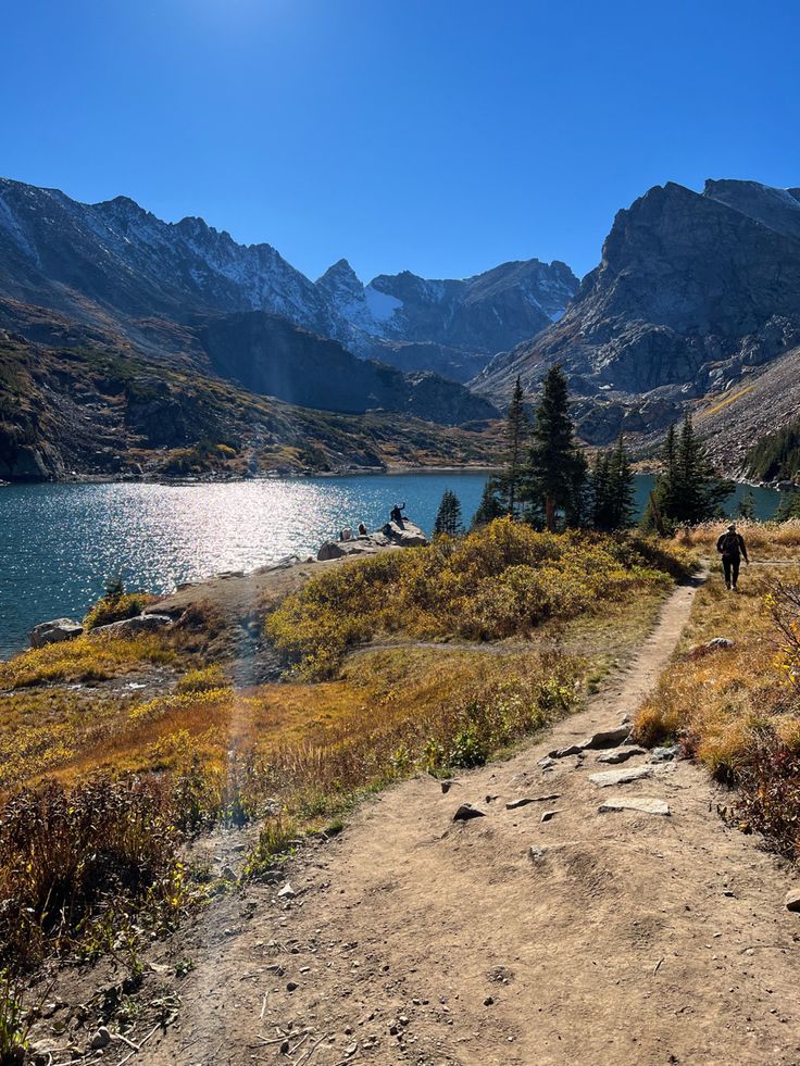 a trail leading to a lake with mountains in the background