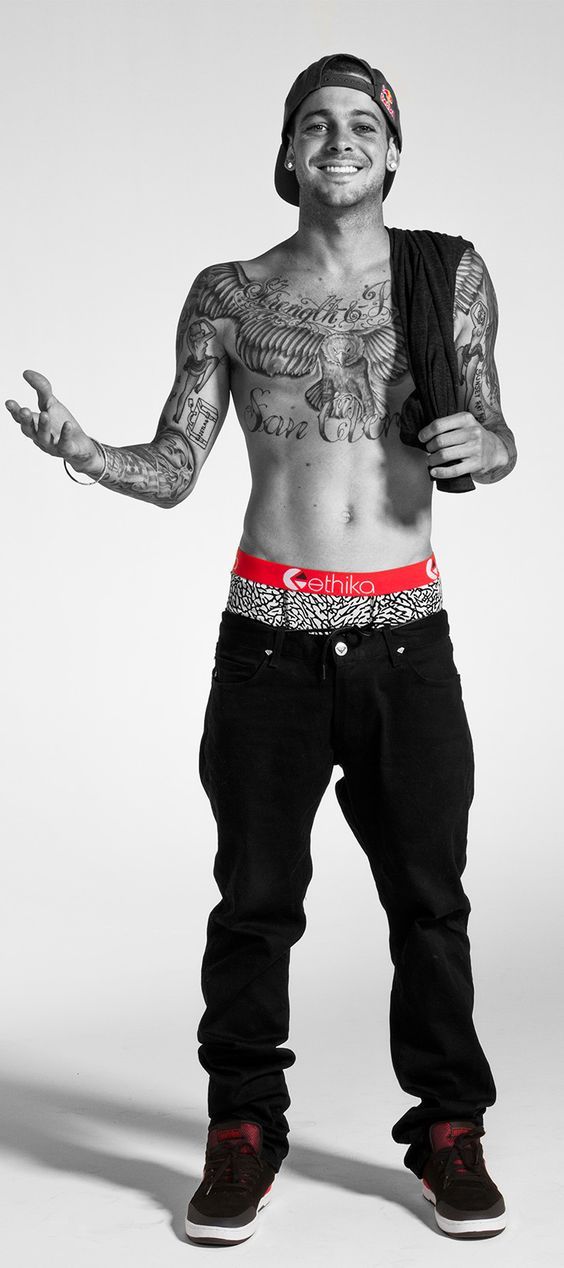 a man with tattoos and no shirt standing in front of a white background