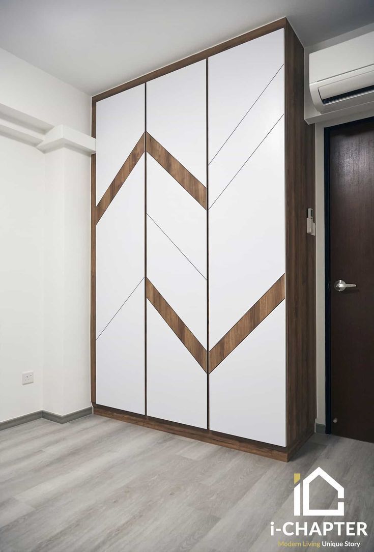 an empty room with white and brown furniture in it's corner, next to a black door