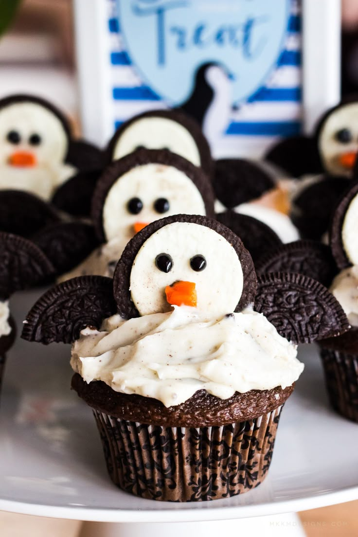 some cupcakes with frosting and penguins on them