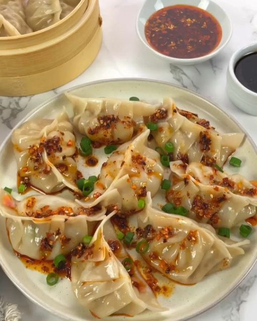 some dumplings are on a plate with sauces and seasoning next to them