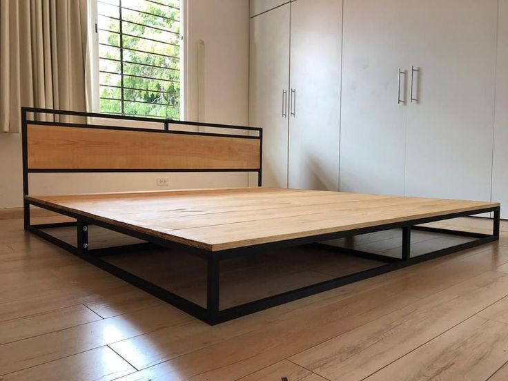 a bed frame sitting on top of a hard wood floor next to a white wall