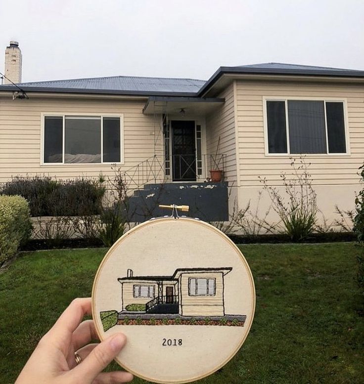 a person holding up a small embroidered house