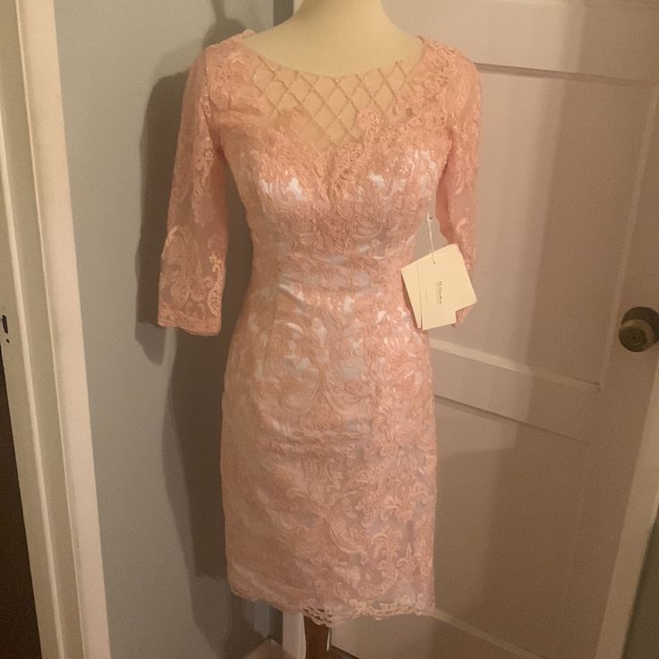 a pink dress on a mannequin stand in front of a door with a tag