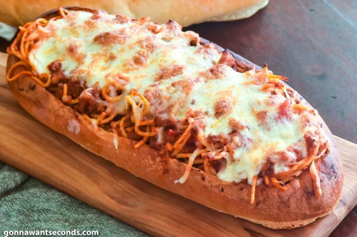 a cheesy bread with meat and cheese on it sitting on a cutting board