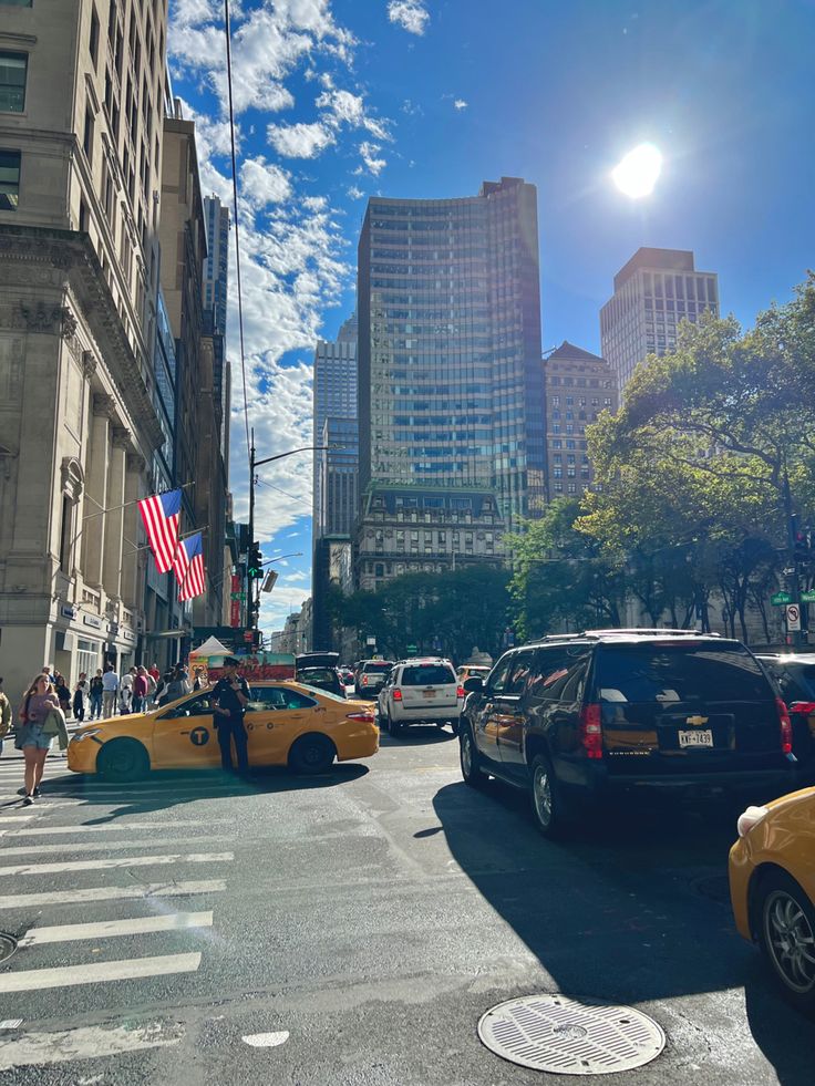 taxi cabs and taxis on a city street with tall buildings in the background at sunny day