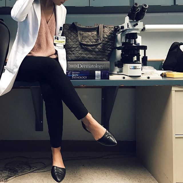 a woman sitting at a desk in front of a microscope