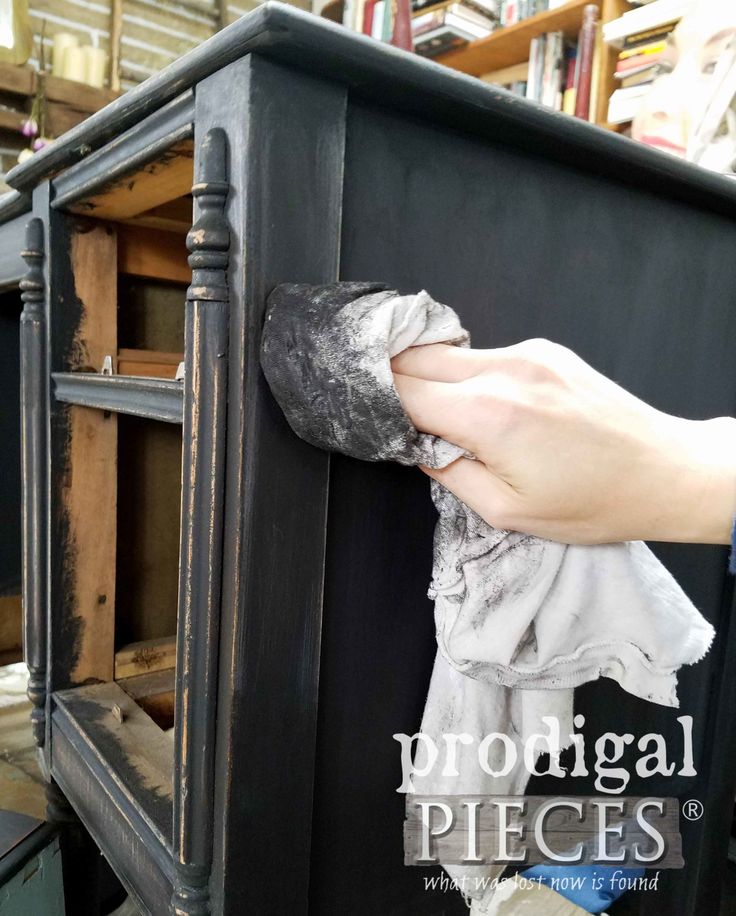 a person is cleaning an old black cabinet