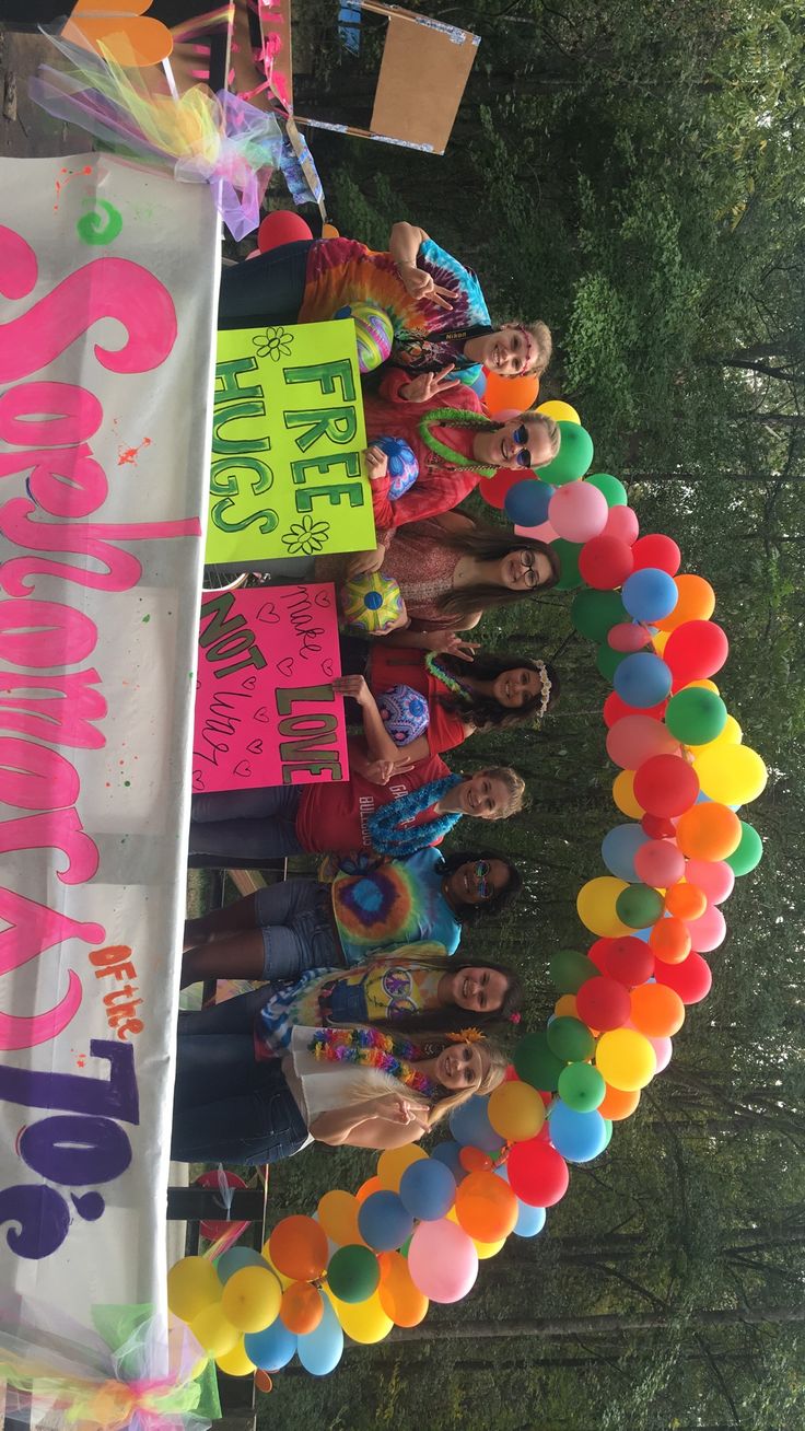 a group of people standing next to each other near a sign with balloons on it