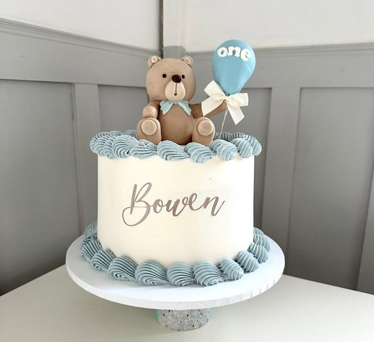 a teddy bear sitting on top of a cake with balloons in the shape of hearts