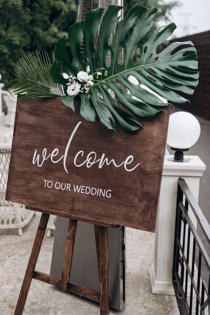 a welcome sign with greenery on it