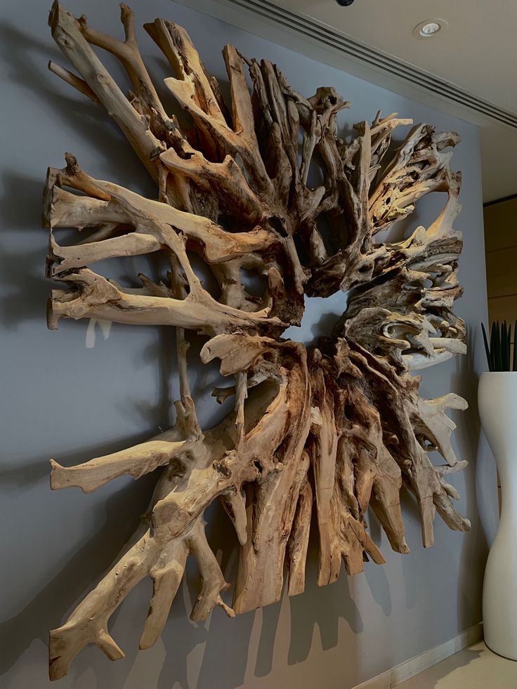 a large piece of driftwood is mounted on the wall next to a vase with flowers in it