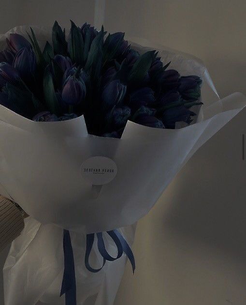 a bouquet of purple tulips in a white paper bag