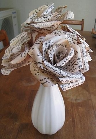 a white vase filled with paper flowers on top of a wooden table