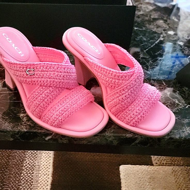 a pair of pink shoes sitting on top of a table next to a box and remote control