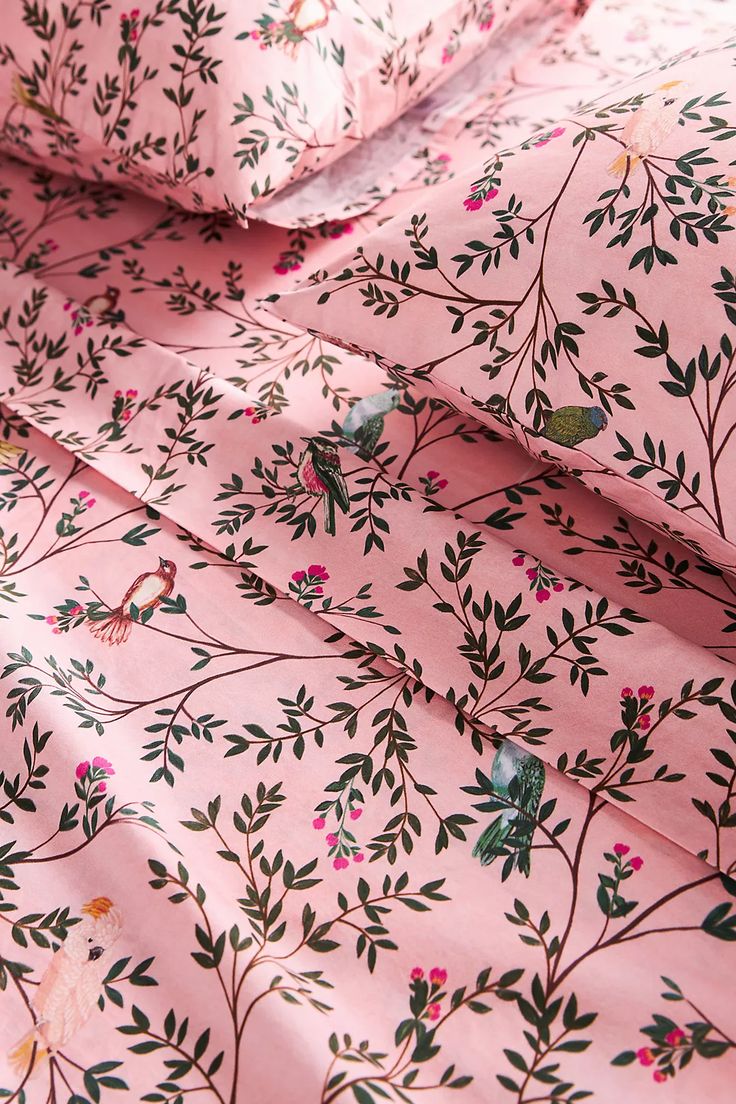 pink floral bedding with green leaves and birds on the sheet set, close up