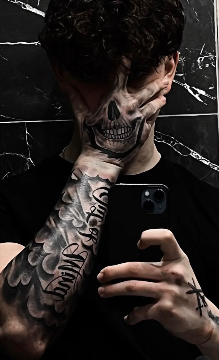 a man with tattoos on his face and arm holding a cell phone in front of him