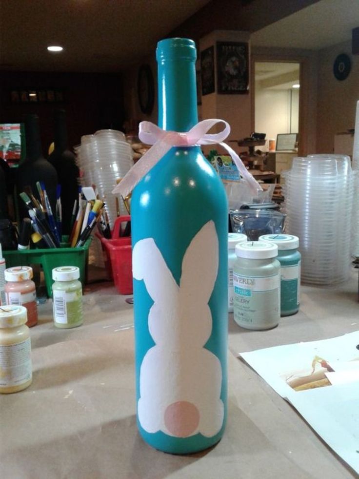 a blue bottle with a bunny on it sitting on a counter next to other crafting supplies