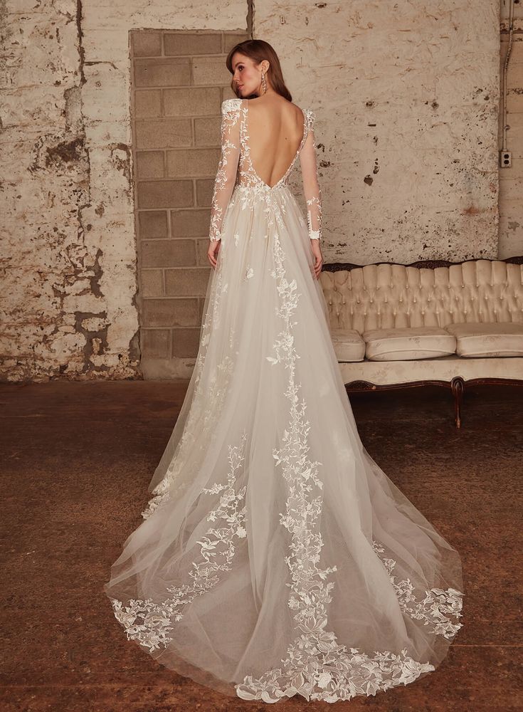 the back of a wedding dress with long sleeves and floral appliques on it