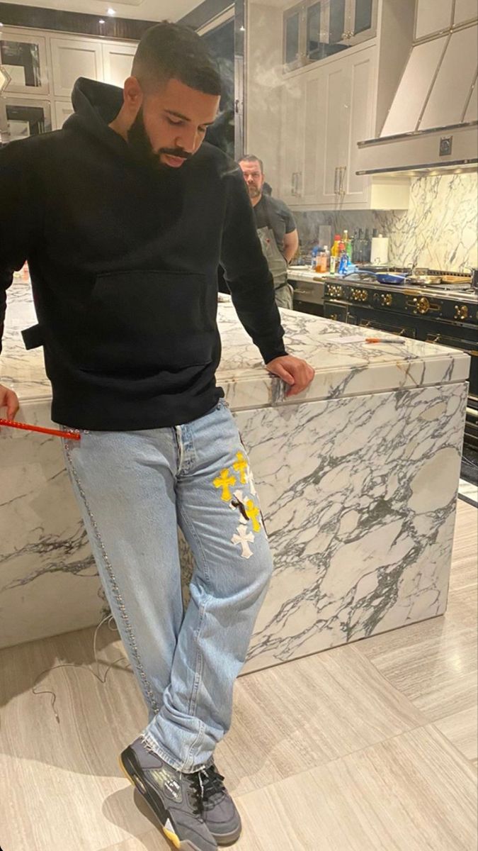 a man standing on top of a counter in a kitchen next to a marble counter