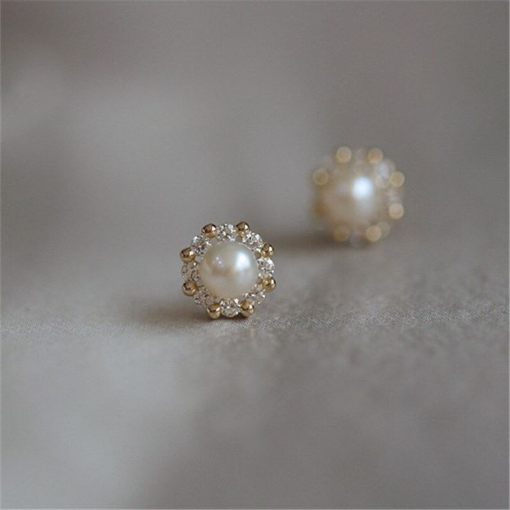 Simple and timeless. Every girl needs a pair of classic pearl studs in their jewelry box! This pair has a modern twist, with a 14K gold or silver halo of alternating CZ stones and shiny beads surrounding a gorgeous faux pearl. DETAILS & SIZE Sold as a pair Composition: 14K gold plated over .925 sterling silver or solid .925 sterling silver; CZ stones; faux pearl Measurements: 7mm Comes with friction earring backs Read about how to care for your jewelry here. Shop the Ear Bar to curate your ear s Small Earrings Gold, Top Earrings, Stud Earrings Women, 14k Gold Plated Jewelry, Silver Pearl Earrings, Simple Pearl, Indian Gowns, Fashion Enthusiast, Jewelry Simple