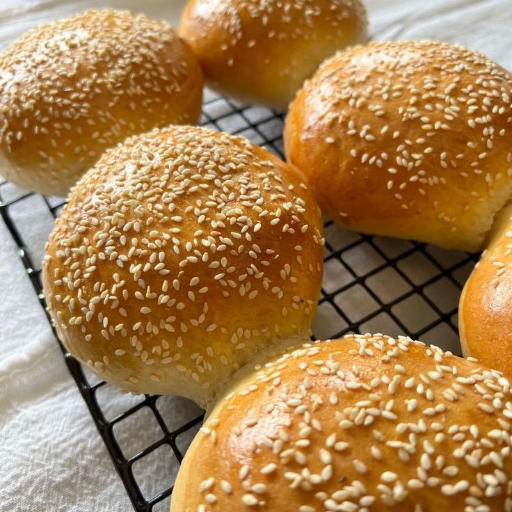 six sesame seed bagels on a cooling rack