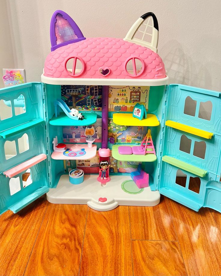 a doll house with lots of furniture and accessories in the middle of it on top of a hard wood floor