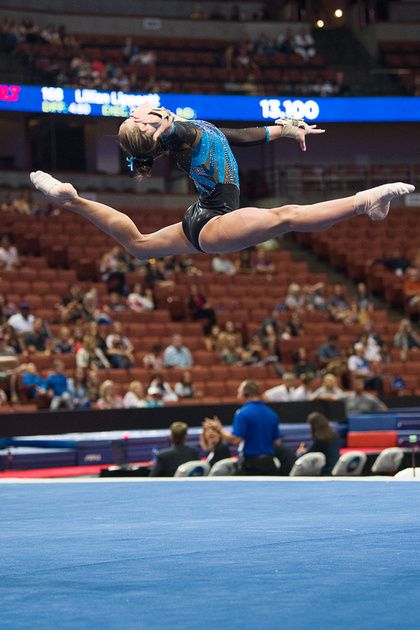 a woman is doing an acrobatic trick in front of a crowd at a sporting event