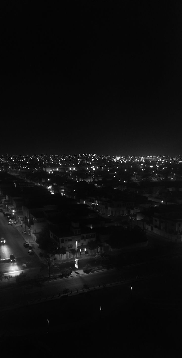 black and white photograph of city at night with lights in the dark, taken from an airplane