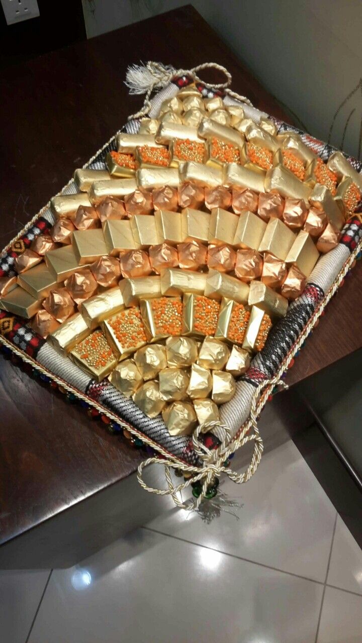 a tray filled with lots of different types of gold and chocolates on top of a wooden table